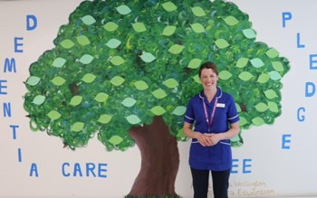 Staff member in front of tree decoration on wall