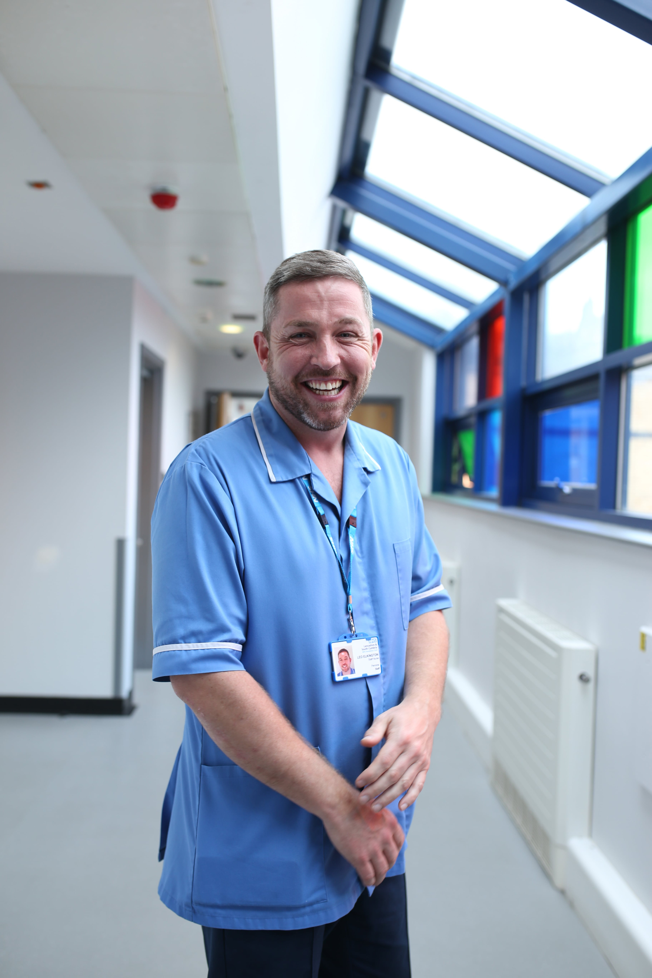 Nurse stands laughing and looking at the camera