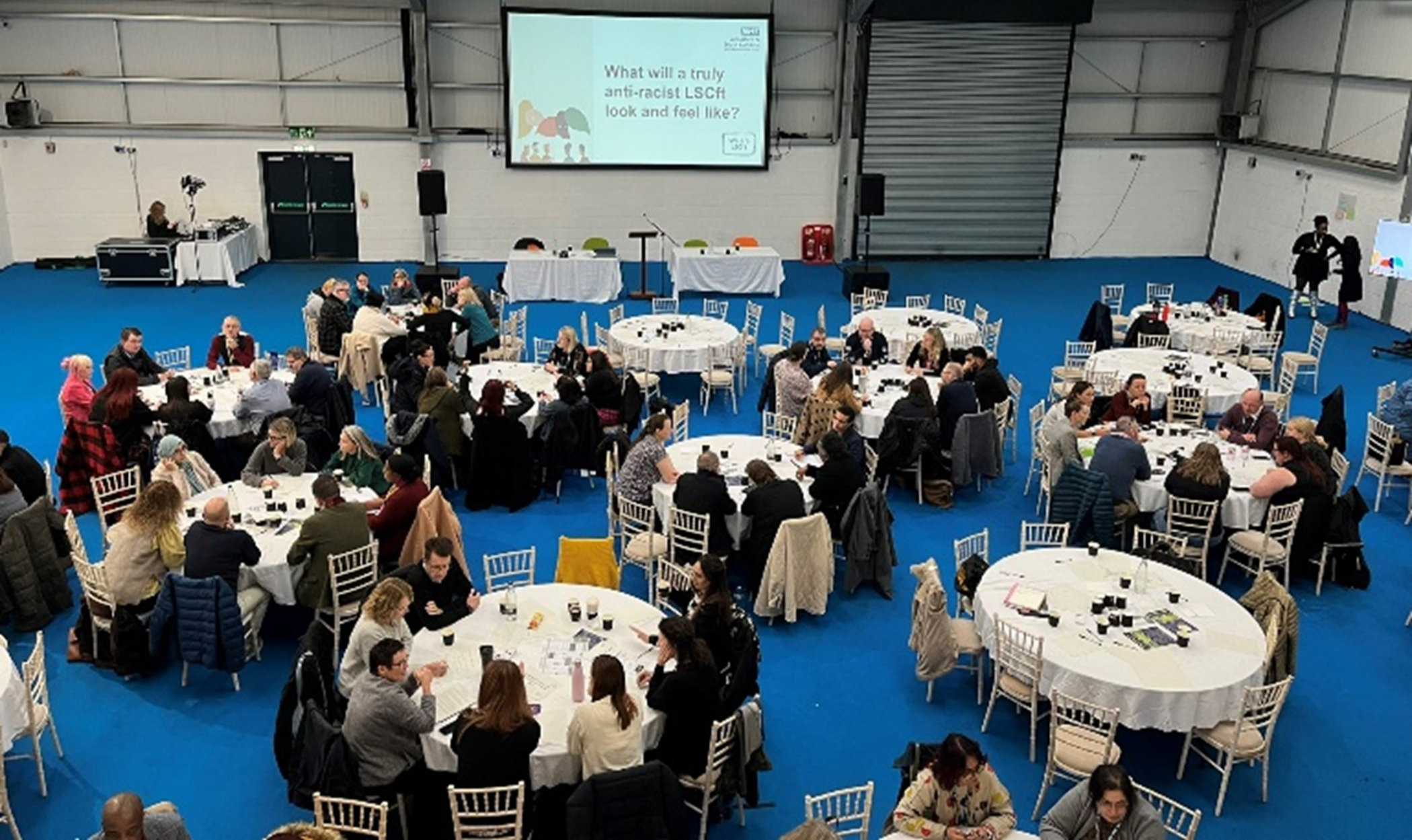 View from above, people sat round tables at a conference.