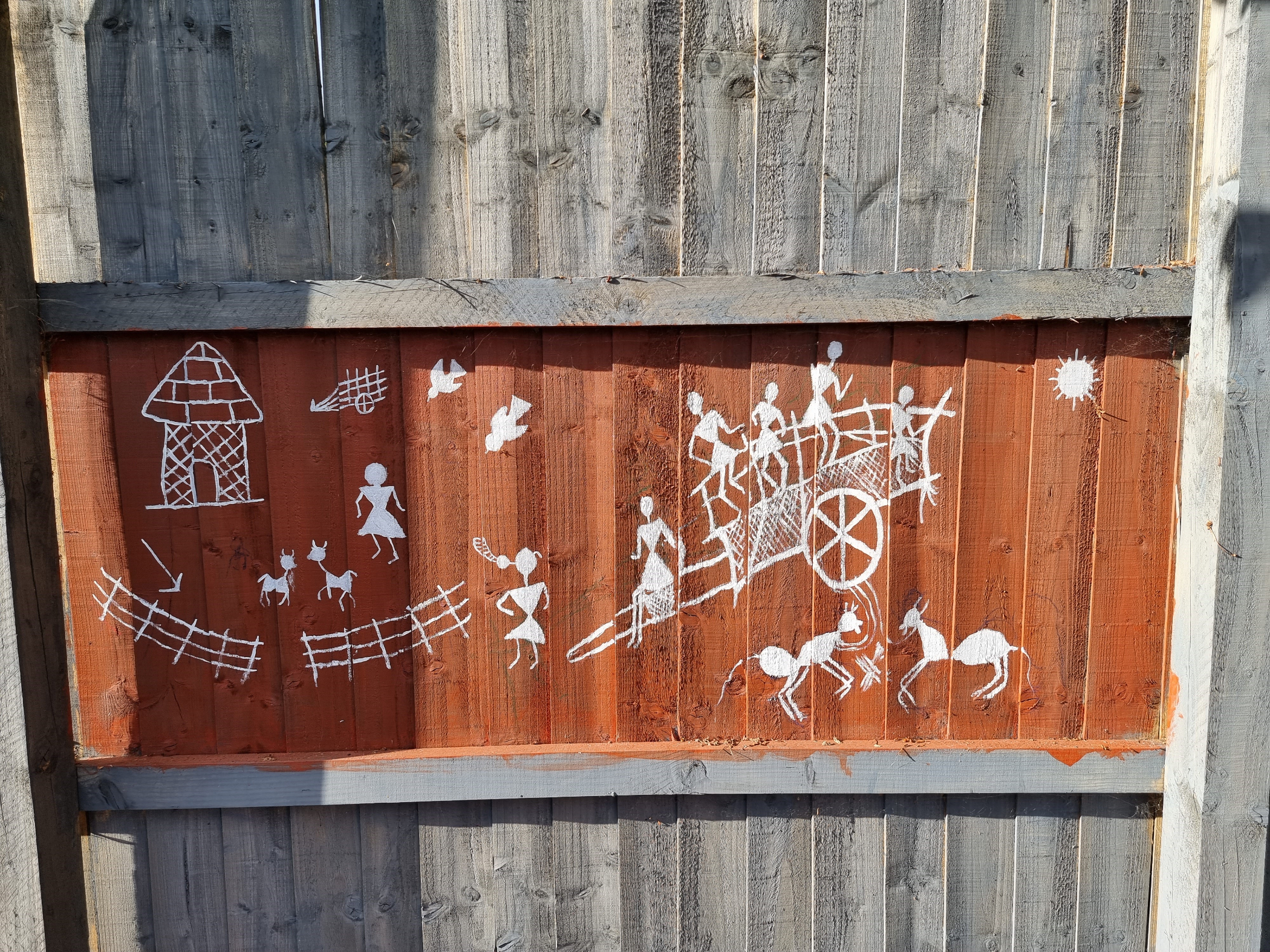 Painting on fence of white stick people