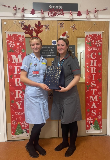 A healthcare support worker and matron holding a gift